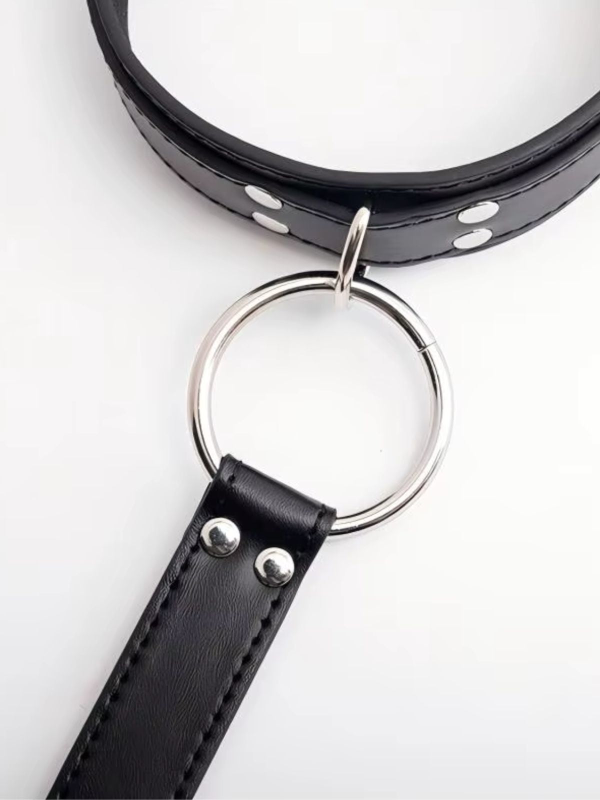 bdsm restraints collar ring close up with black faux leather strap and silver hardware