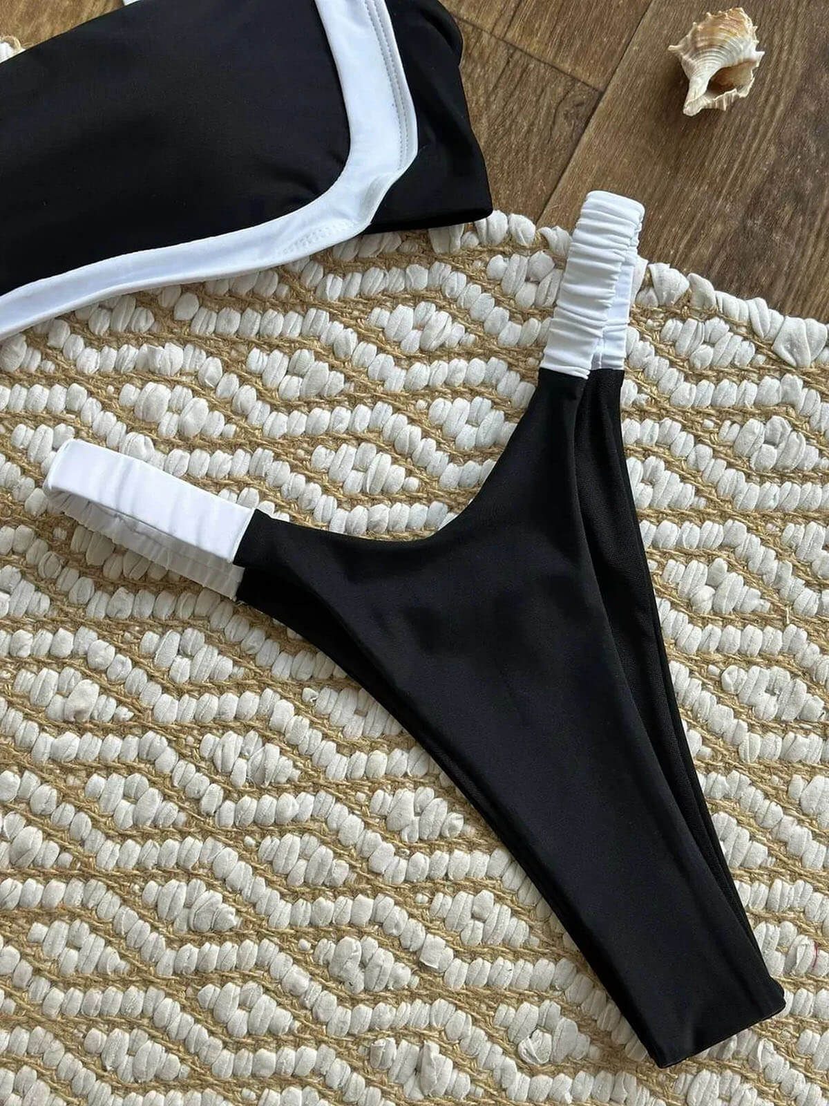 black bikini with white trim high leg bottoms flat lay with ruched side straps