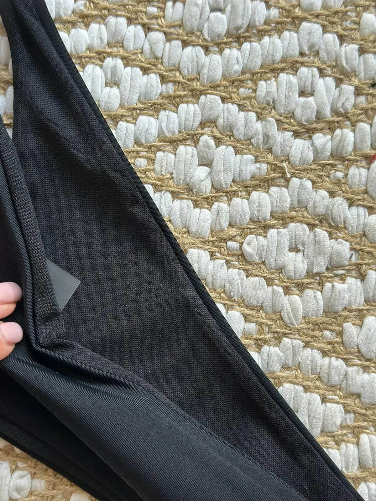 black bikini with white trim fabric close up showing smooth material and inner lining