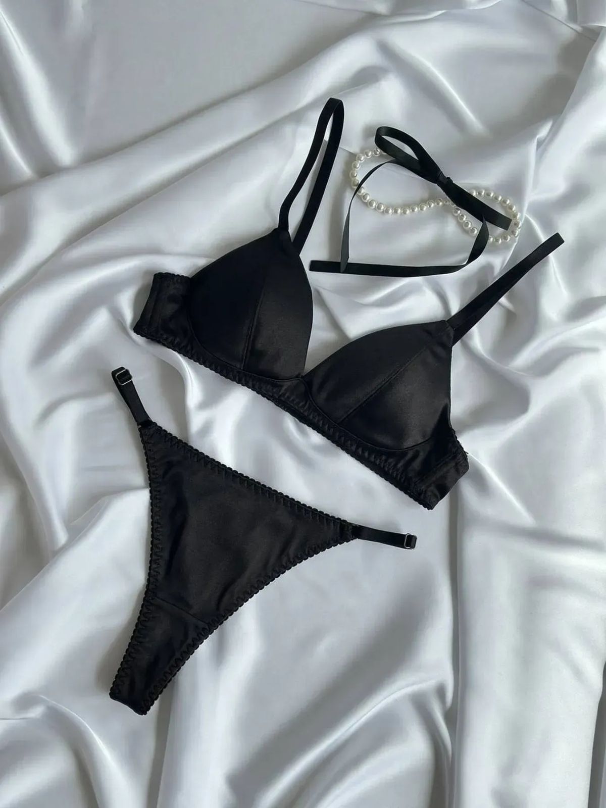 black push up bra set flat lay, matching bra and thong on silky satin background