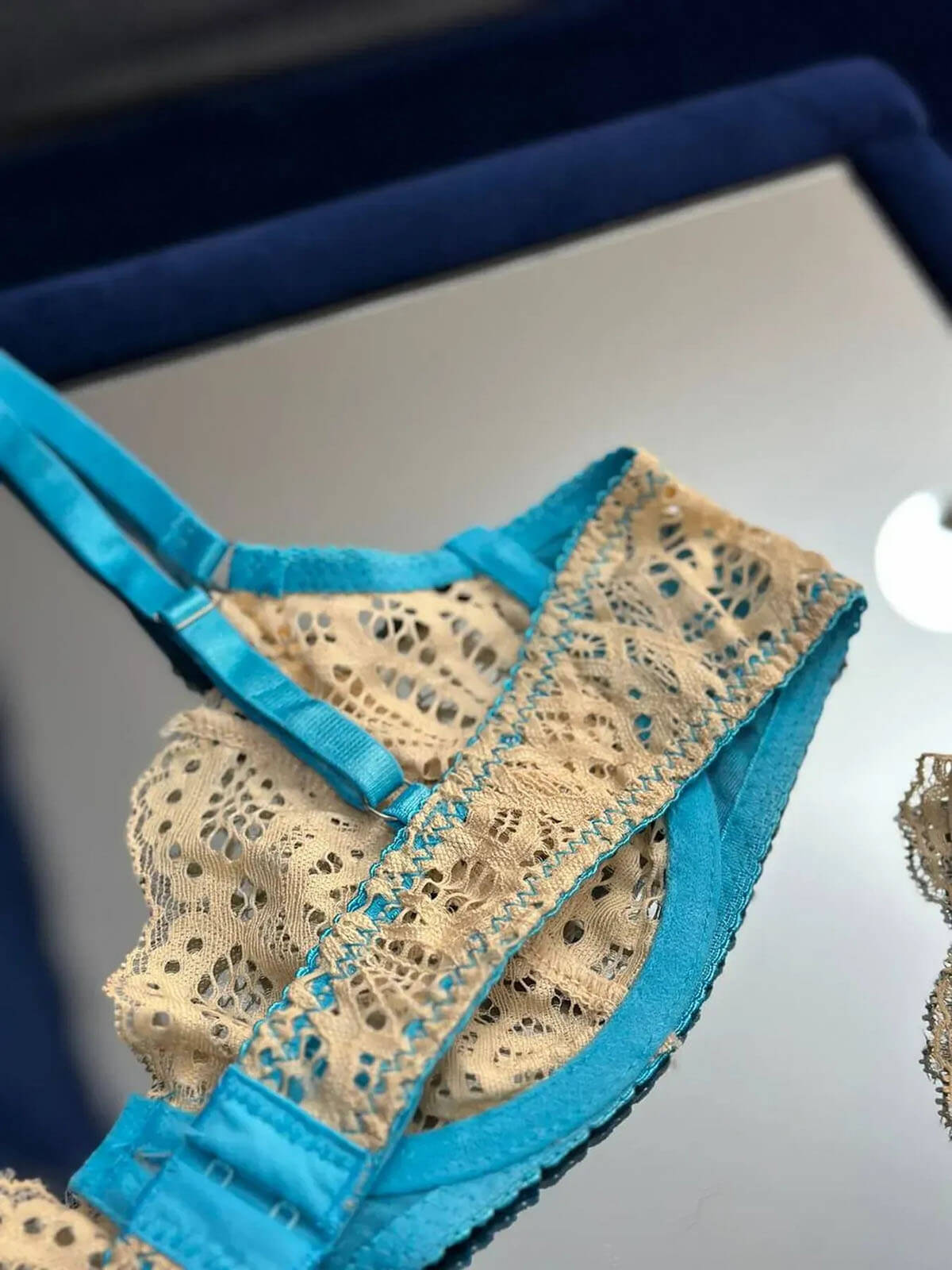 Close-up shot of a blue lace lingerie set showing intricate lace detail and satin finish.