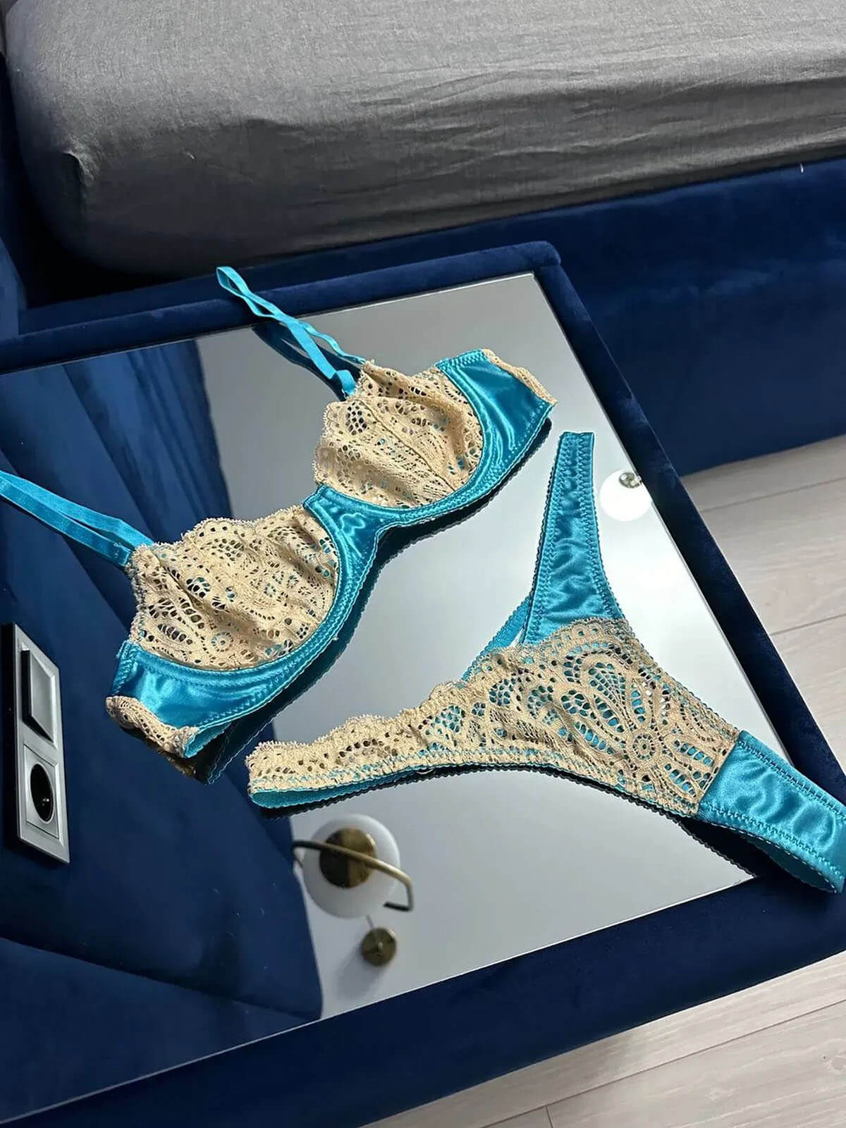 Close-up front view of a blue lace lingerie set showing the lace details and satin straps.