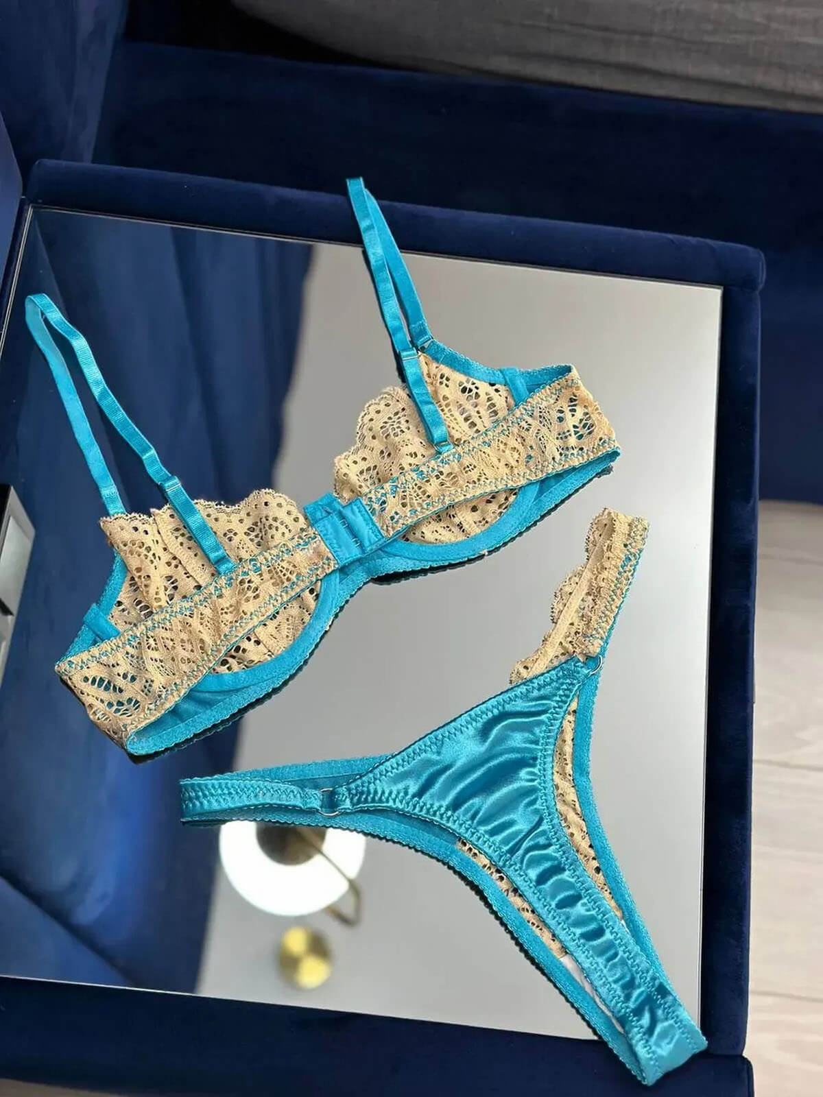 Side view of a model wearing a blue lace lingerie set with lace details and satin fabric.