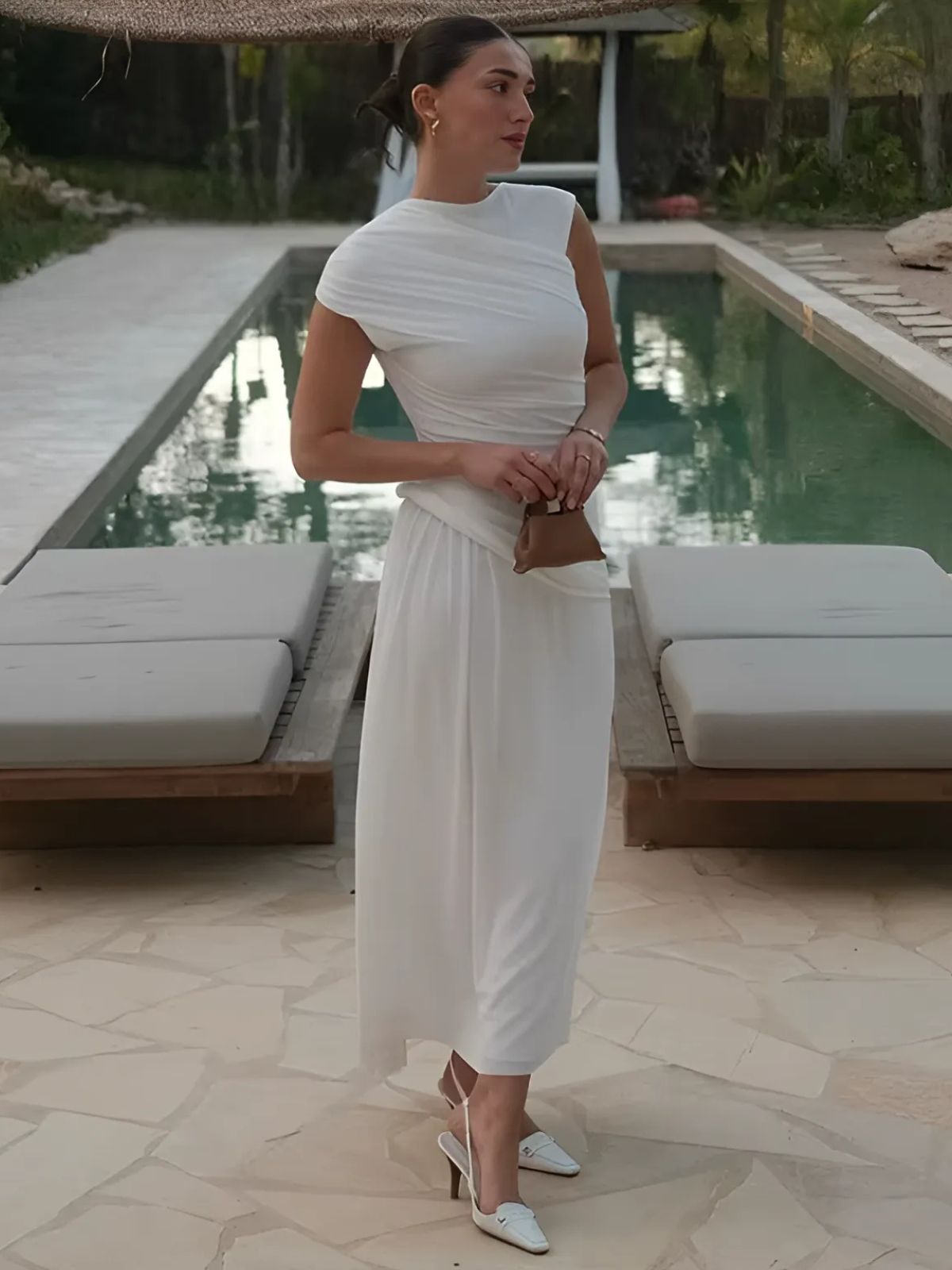 Chic white bodycon maxi dress styled by the pool, perfect for summer or vacation looks.