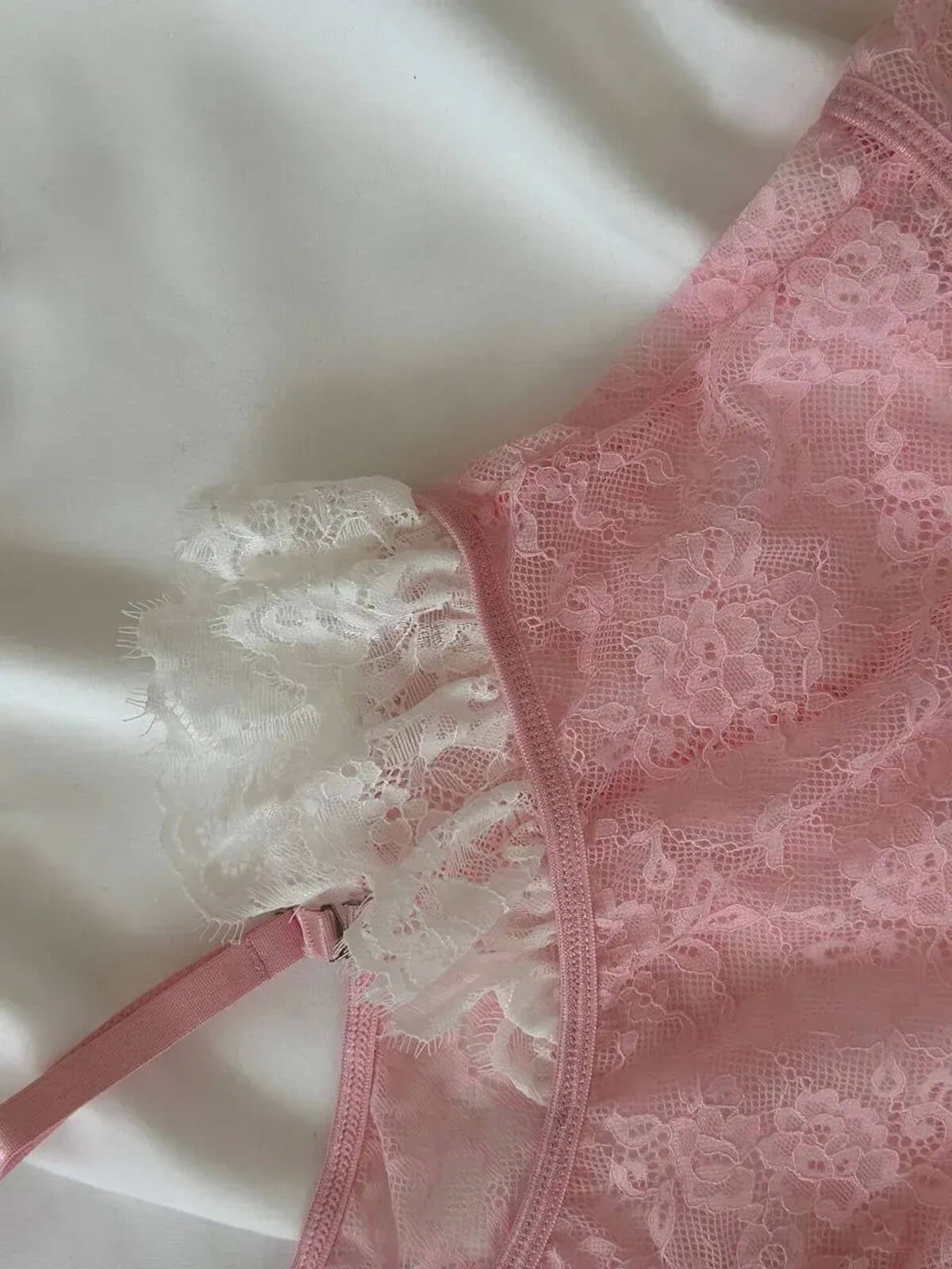 lace teddy bodysuit close up of pink lace fabric, white ruffle trim and garter strap detail