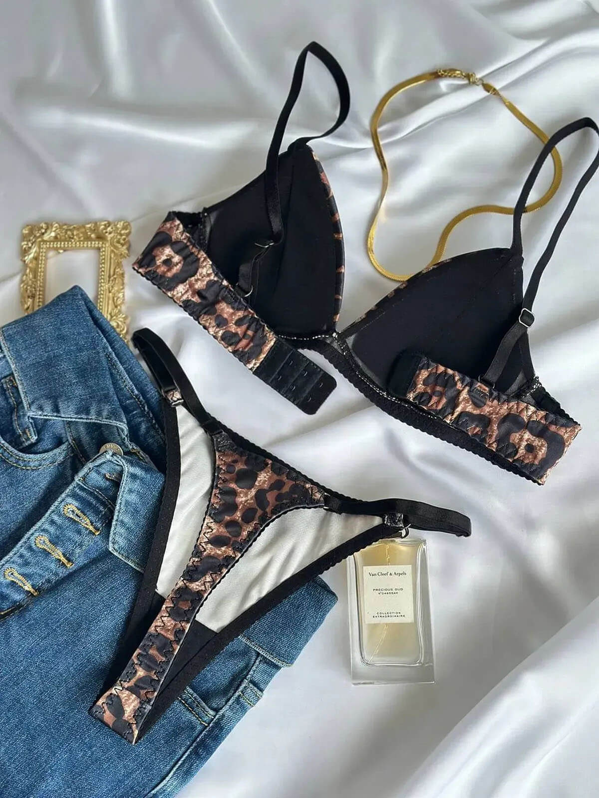 Leopard Print Lingerie Pushup bra and thong flat lay on satin with jeans, gold accessories and perfume