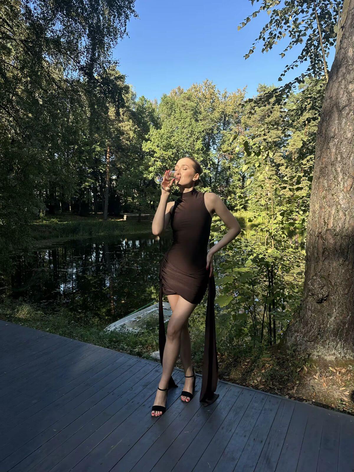 Luna Ruched Mini Dress styled outdoors in a natural setting with green trees in the background.