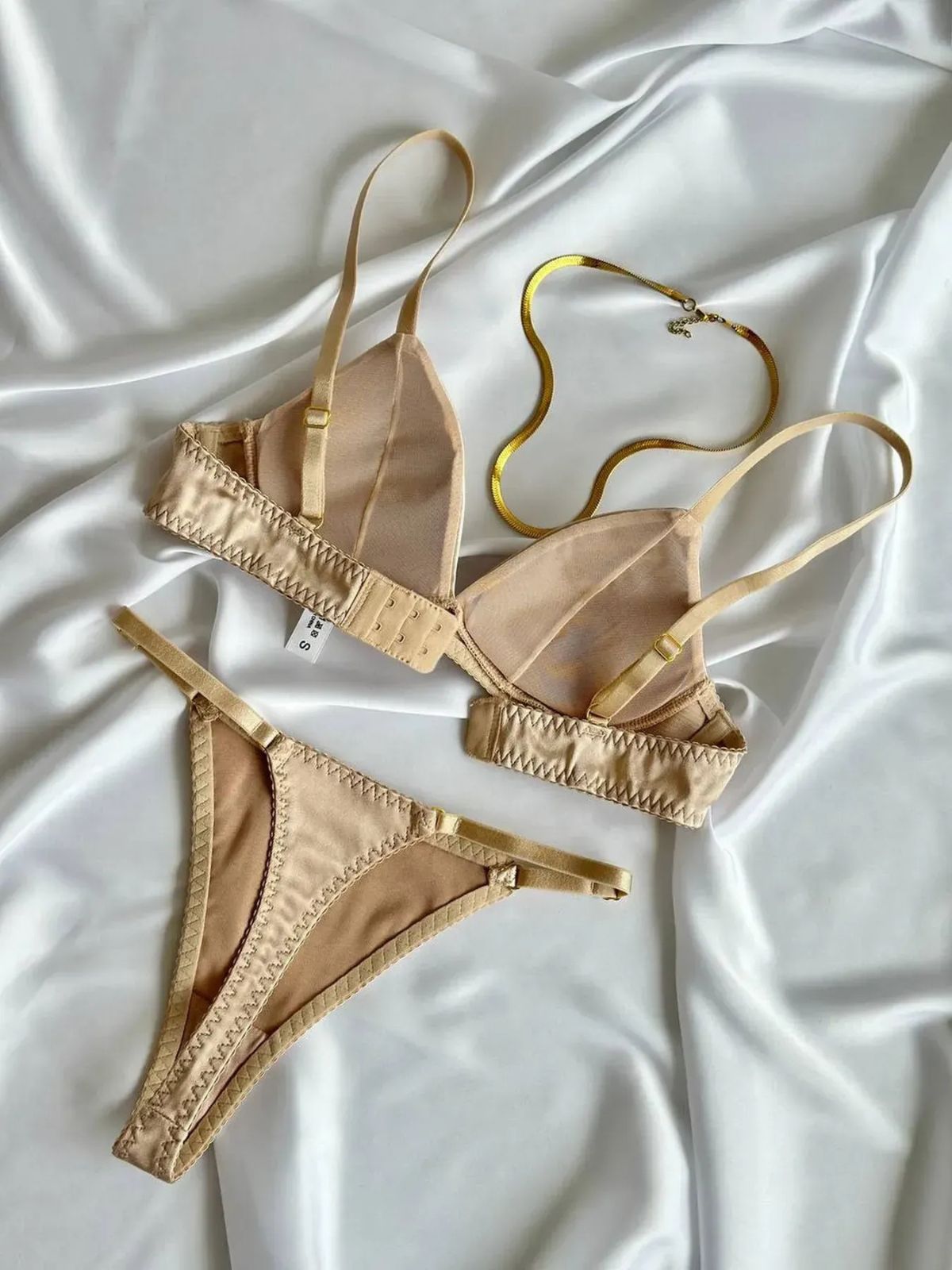 nude push up bra and thong set flat lay, inside cup and clasp details on silky white backdrop