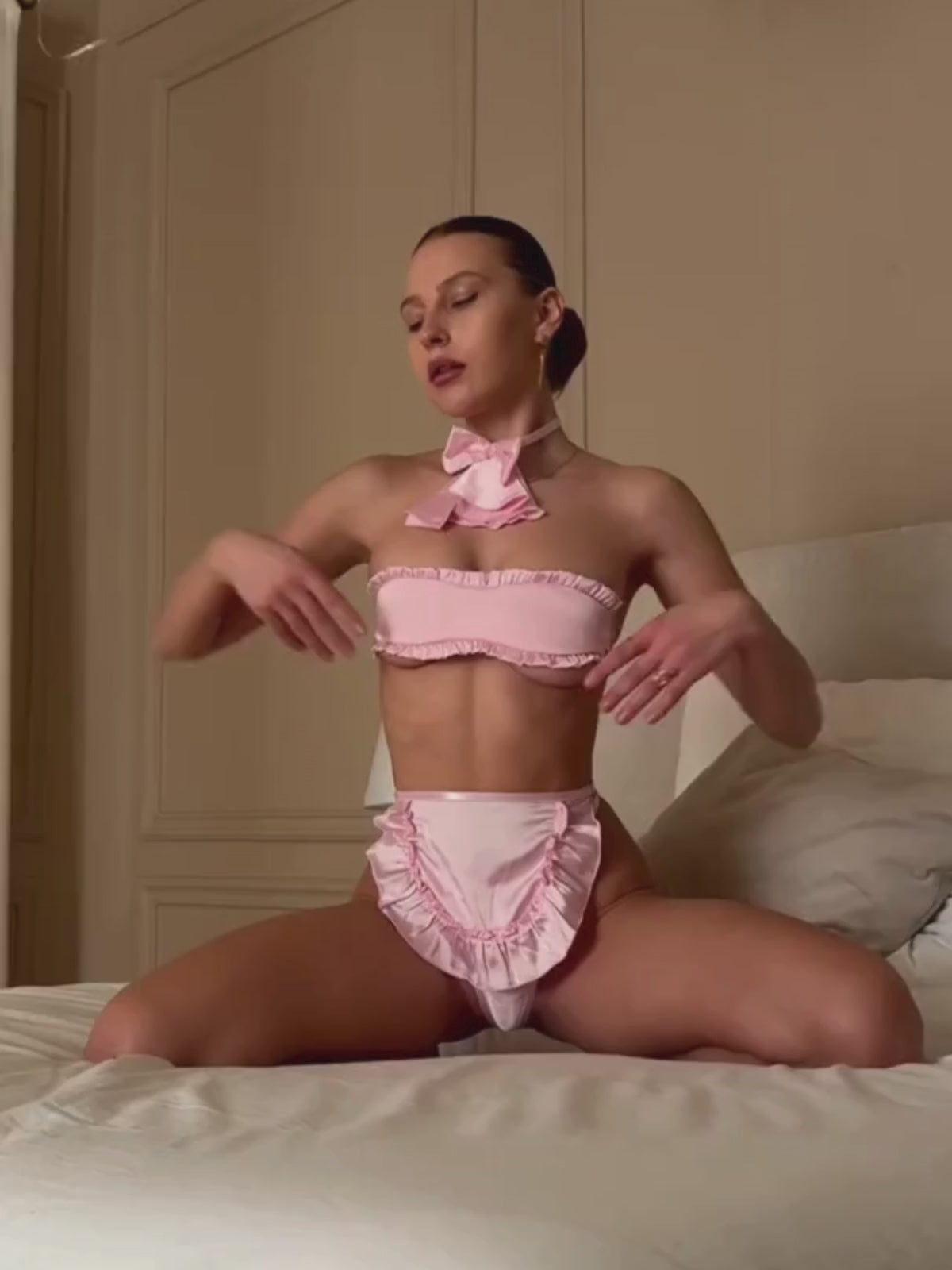 Load video: Pink Maid Lingerie Set video showing bandeau top, ruffle apron thong and bow neck scarf in motion