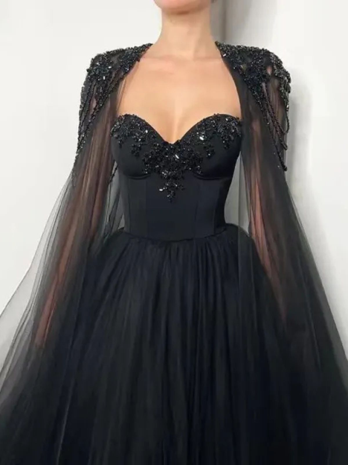 Raven Noir Embellished Wedding Gown featuring sheer cape sleeves and intricate embellishments for a dramatic bridal look.
