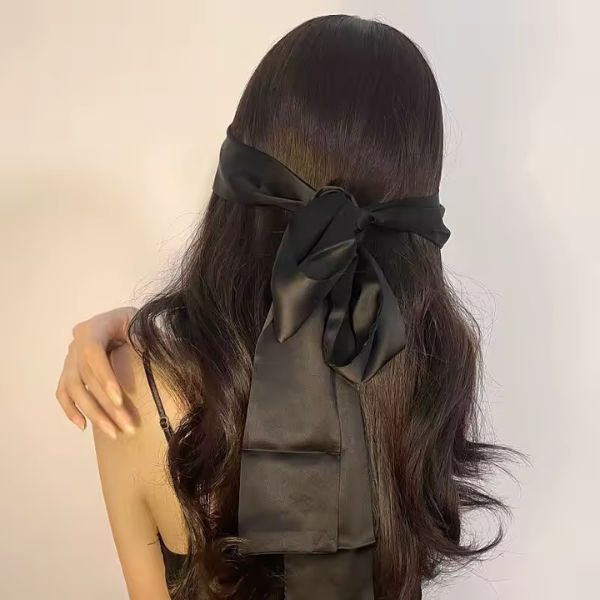 Satin Bow Bedroom Cuffs in black satin laid flat with long tapered ends