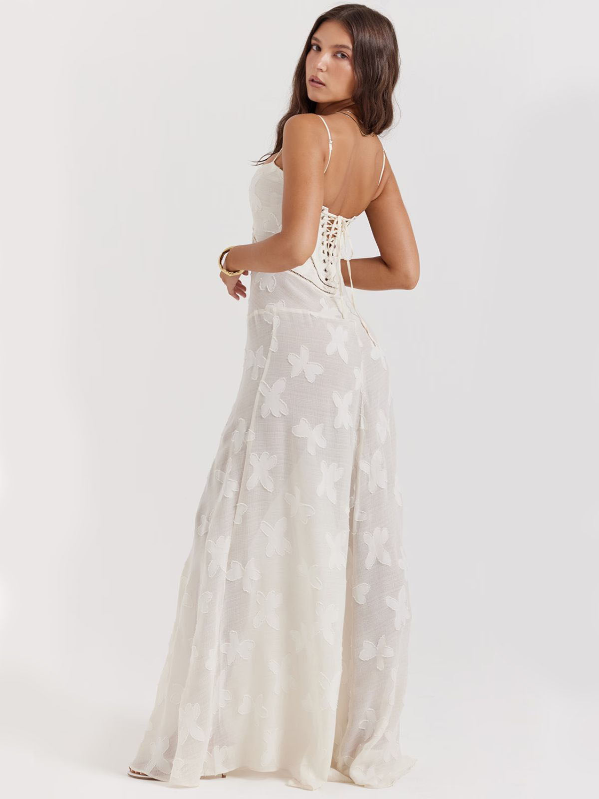 Model posing in white floral dress with a flowing maxi design, perfect for sophisticated evenings or bridal occasions.